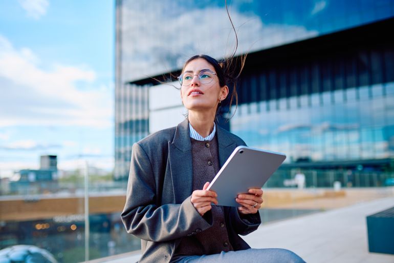 Businesswoman holding tablet looking up envisioning future المصدر: أدوبي ستوك