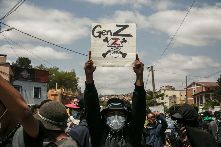 A protester holds a placard during a demonstration against repeated water and electricity outages in Antananarivo on September 27, 2025. Hundreds of mostly young protesters faced off against security forces in Madagascar's capital on September 27, 2025 days after an anti-government demonstration erupted into clashes and looting.