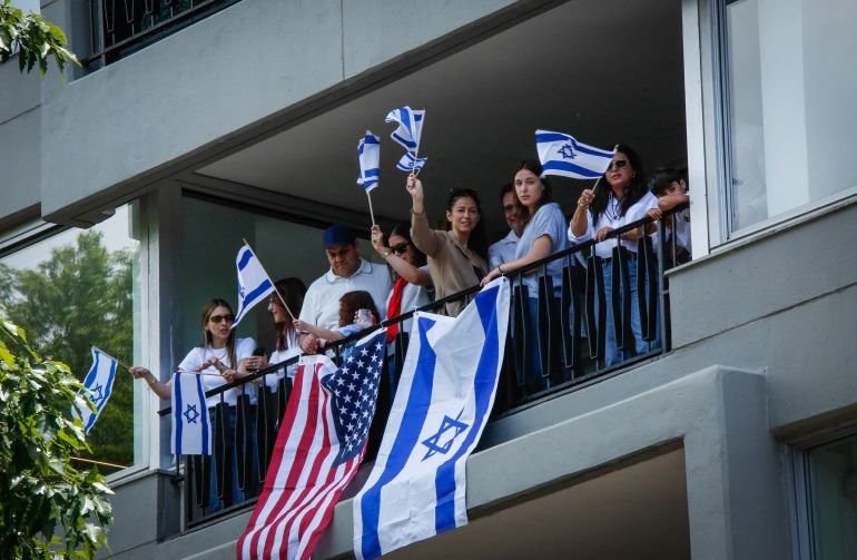 People wave Israeli and US flags from a balcony on Fifth Avenue as they watch the Israel Day Parade in New York on May 31, 2026. (Photo by kena betancur / AFP)