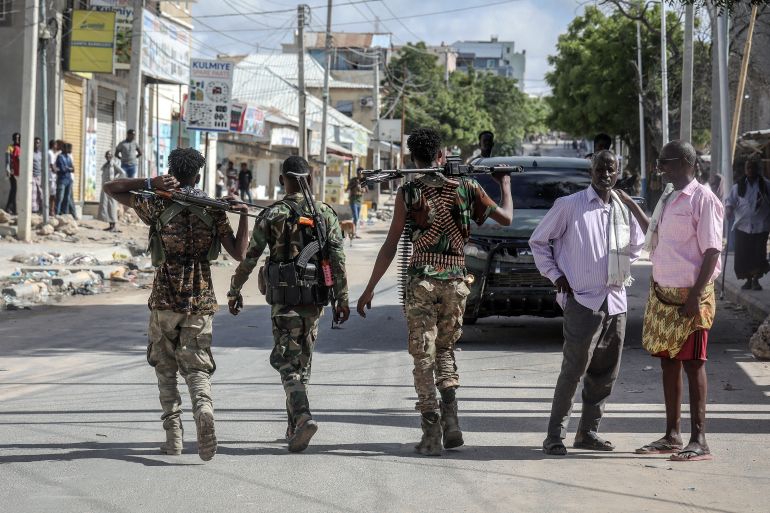 TOPSHOT - Somali government forces patrol a street as residents gather following reported shelling in the Howl Wadaag district of Mogadishu, on June 4, 2026.
