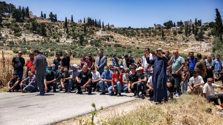 Palestinians block a road as they gather to perform the Friday Muslim noon prayers and to protest the reported burning of land by Israeli settlers in the Palestinian village of Idna, west of Hebron in the occupied West Bank, on June 5, 2026.