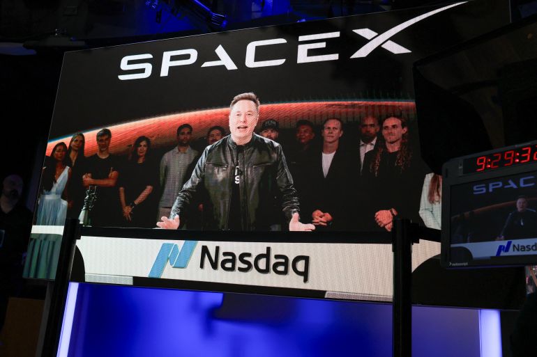 afp_6a2d056b3829-1781335403-1 SpaceX CEO Elon Musk, displayed on a screen remotely from SpaceX headquarters in Starbase, Texas, speaks before the launch of SpaceX’s initial public offering (IPO) at the Nasdaq MarketSite in New York on June 12, 2026.