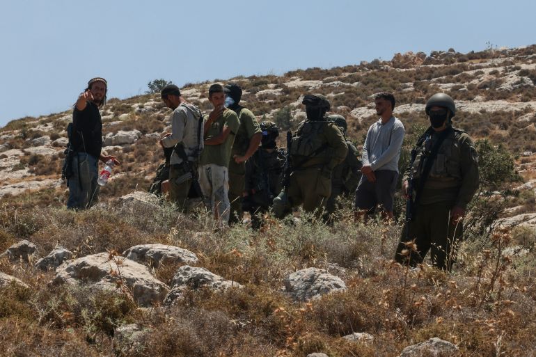 afp_6a3230f23555-1781674226 Israeli forces and armed settlers guard a bulldozer reportedly operating on Palestinian lands as local Palestinian landowners (unseen) gather in protest against land confiscations near the village of Dura, west of Hebron in the Israeli-occupied West Bank, on June 9, 2026.