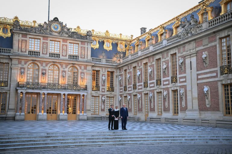 France's President Emmanuel Macron (L) and his wife Brigitte Macron (C) welcome US President Donald Trump (R) at Chateau de Versailles ahead of a dinner to celebrate the 250th anniversary of the independence of the United States, in Versailles southwest of Paris on June 17, 2026. (Photo by Mandel NGAN / AFP)