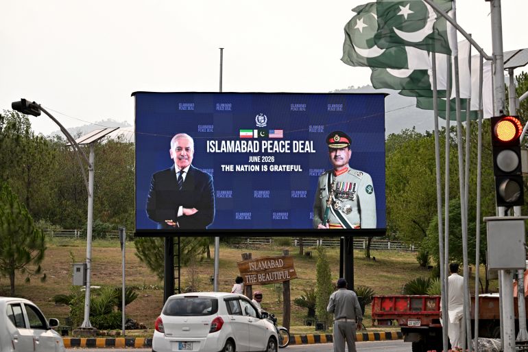 afp_6a338d903eb8-1781763472 Commuters ride past an electronic board featuring Pakistan's Prime Minister Shehbaz Sharif (L) with Army Chief and Field Marshal Syed Asim Munir, displayed along a roadside in Islamabad on June 17, 2026, after the US–Iran peace deal announcement.