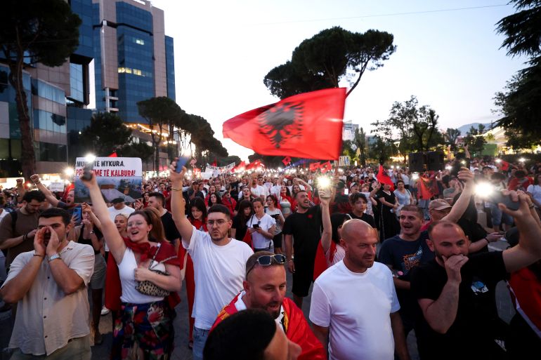 afp_6a3603113f76-1781924625 Protestors hold placards and Albanian national flags as they gather in front of Albania's Prime Minister's Office during a demonstration against a luxury resort development near a protected natural area, in Tirana on June 19, 2026.