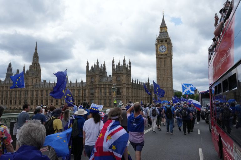 afp_6a38798e414e-1782086030 People wave flags and hold banners as they march over Westminster Bridge during a National 'Rejoin the EU' march in central London on June 20, 2026.