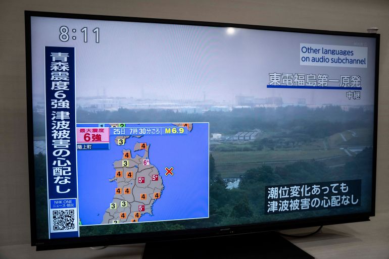 An advisory reading 'Intense tremors measuring upper 6 on the Japanese seismic scale hit Aomori. No risk of a tsunami.' is seen with the live footage of Fukushima Daiichi Nuclear Power Station, on a television screen in Kawasaki, Kanagawa prefecture on June 25, 2026. (Photo by Yuichi YAMAZAKI / AFP)