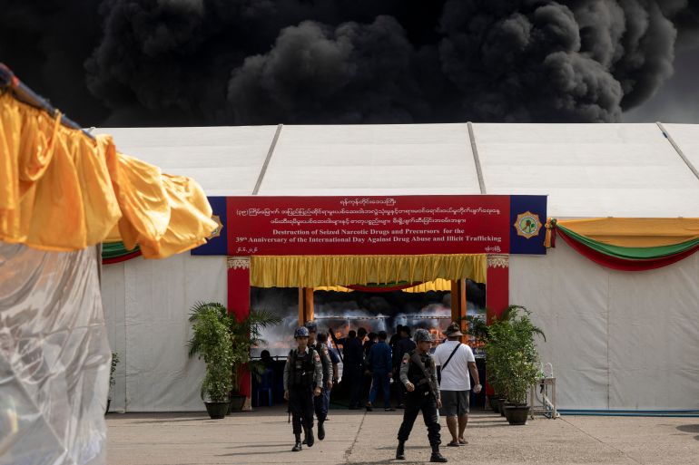 Officials stand as smoke rises during a destruction ceremony of seized illegal drugs to mark the United Nations' "International Day against Drug Abuse and Illicit Trafficking" in Yangon on June 26, 2026. (Photo by Sai Aung MAIN / AFP)