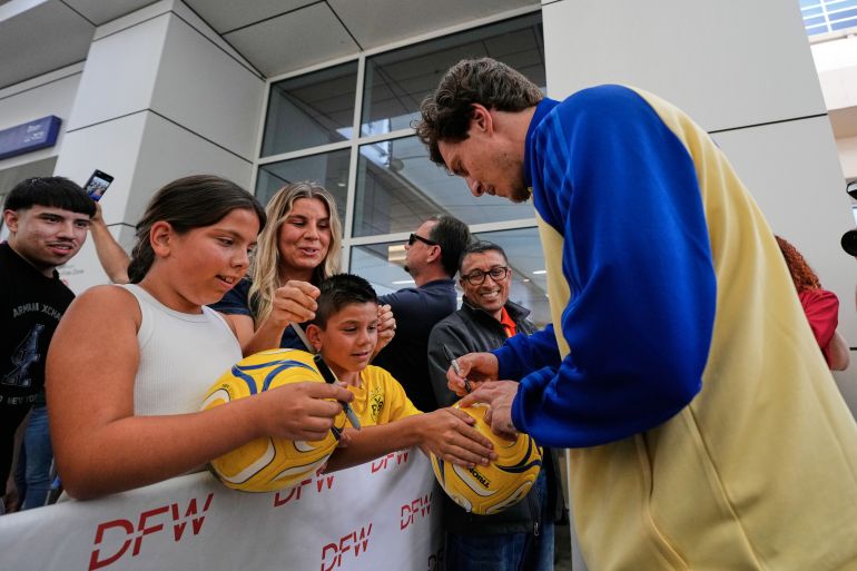Sweden's Victor Lindelof, right, signs autographs for Zain and Zara Sagiri of Flower Mound, Texas, as their mother Linda, center rear, looks on after the team arrived at the Dallas Fort Worth International Airport, at DFW Airport, Texas, Saturday, June 6, 2026, ahead of the World Cup soccer tournament. (AP Photo/Tony Gutierrez)