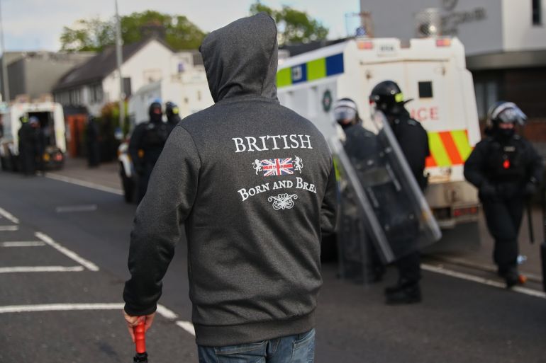 ap_6a2a399639f5b-1781152150 Police in riot gear watch protesters following near Newtownabbey, in Belfast, Northern Ireland, Wednesday, June 10, 2026, following a stabbing incident on Monday night. (AP Photo/Peter Morrison)