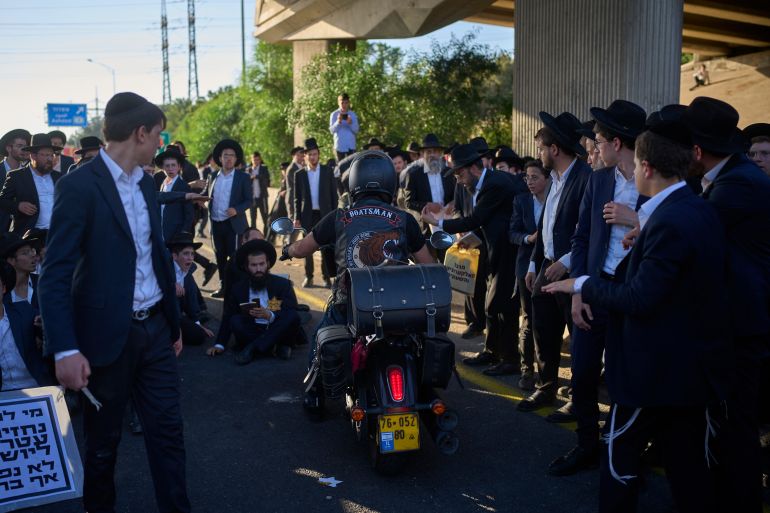 Ultra-Orthodox Jewish men block a main road during a protest against military recruitment near Tel Aviv, Israel, Thursday, June 11, 2026. (AP Photo/Ohad Zwigenberg)