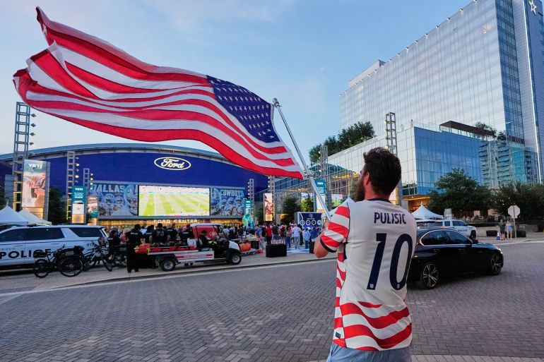 ap_6a2d33c22cf1e-1781347266 Spencer Simkins of Frisco, Texas, waves an American flag as he joins a watch party for the World Cup Group D soccer match between Paraguay and the US at The Star, headquarters of the Dallas Cowboys football team, Friday, June 12, 2026, in Frisco, Texas. (AP Photo/Tony Gutierrez)