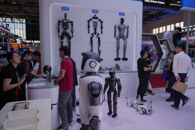 Workers attend to visitors at an exhibition booth promoting humanoid robots and Artificial Intelligence robots at the China International Supply Chain Expo in Beijing, Thursday, June 25, 2026. (AP Photo/Andy Wong)