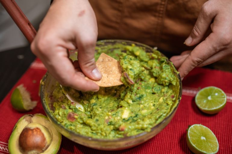 Close-up of homemade guacamole being served with tortilla chips and fresh lime