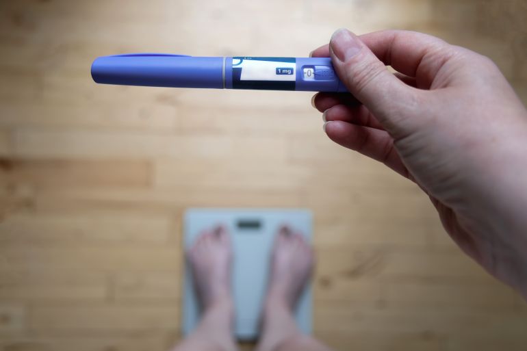 blind3-1720172097 Ozempic Insulin injection pen for diabetics and weight loss. Woman weighs herself and holds Ozempic in her hand. Weight loss concept. Denmark - June 10, 2024