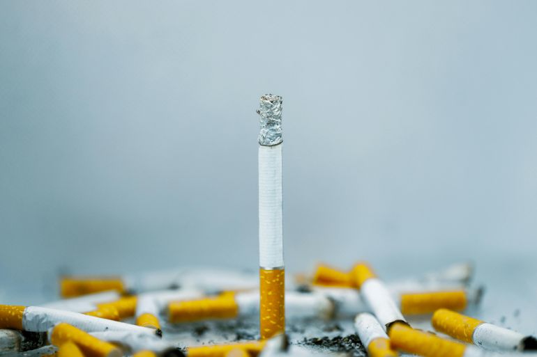 A close-up image of cigarette butts scattered on a white surface, highlighting tobacco addiction.