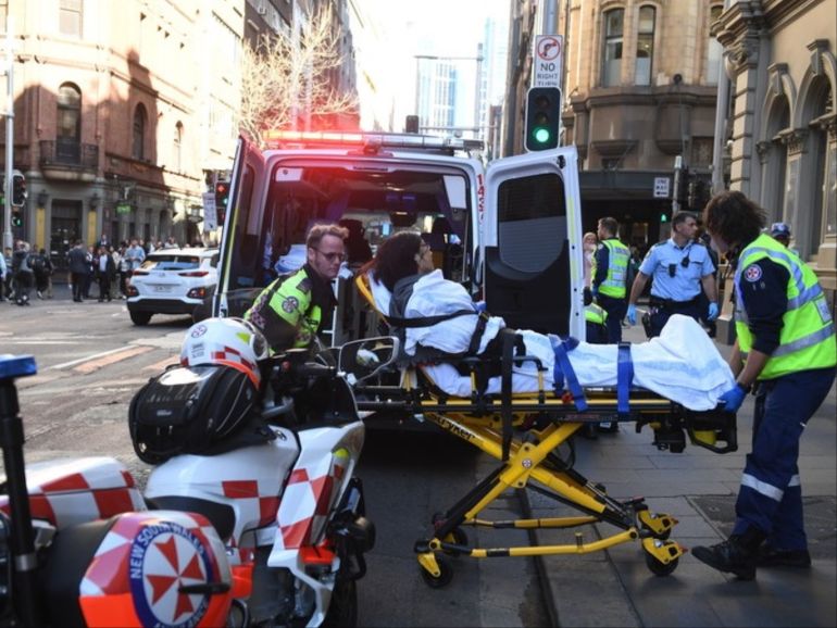 epaselect epa07770604 A woman is taken to an ambulance by paramedics in Sydney, Australia, 13 August 2019. According to media reports a police operation is underway in Sydney's CBD after a person wearing a balaclava stabbed multiple people. Allegedly a man was apprehended in relation to the attacks at Wynyard Station. EPA-EFE/DEAN LEWINS AUSTRALIA AND NEW ZEALAND OUT