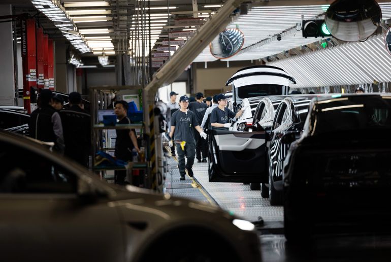 epa12889771 Employees work in the Tesla Gigafactory assembly line, during a government-organized visit, in Shanghai, China, 14 April 2026. Tesla entered the Chinese mainland market in 2013, and on 07 January, 2019, Gigafactory Shanghai broke ground, becoming its first manufacturing facility outside the US by 30 December of the same year. The factory had started delivering 'Made-in-China' Model 3 vehicles. In 2025, Gigafactory Shanghai delivered 851,000 electric vehicles, over half of Tesla's global deliveries that year. The factory serves two roles: manufacturing for the Chinese market and acting as a global export hub. It produces the Model 3, Model Y, and the six-seat Model Y La SUV, which was unveiled in August 2025. China's advanced manufacturing ecosystem and supply chain make Gigafactory Shanghai one of the world's most competitive auto manufacturing sites. EPA/ALEX PLAVEVSKI
