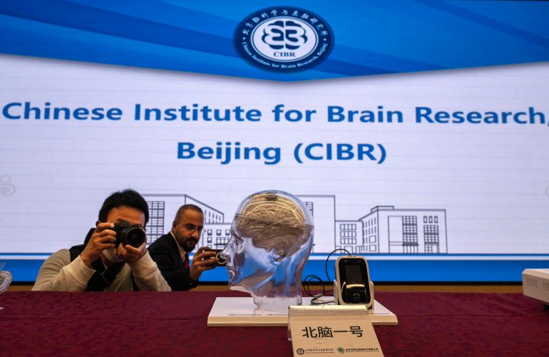 getty_6a08578365-1778931587 BEIJING, CHINA - MARCH 19: Journalists photograph the Beinao-1, a semi-invasive brain-computer interface system, on display at a press conference at the Chinese Institute for Brain Research on March 19, 2026 in Beijing, China. Brain-computer interface, or BCI, is a technology that reads and decodes brain signals to command machines. China's government has been investing heavily in BCI research and development as a "national priority industry" and recently approved a brain implant for use in patients. Clinical trials with similar devices, including one made by NeuCyber NeuroTech at the China Institute of Brain Research, suggest the technology can help people with severe paralysis to regain some ability to communicate and move. The semi-invasive device, about the size of a coin and embedded in the skull, records the brain's electrical activity and sends the information to a computer. Several U.S. companies including Elon Musk's Neuralink have also had breakthroughs in brain technology though China is seen as pushing quickly toward commercialization. (Photo by Kevin Frayer/Getty Images)