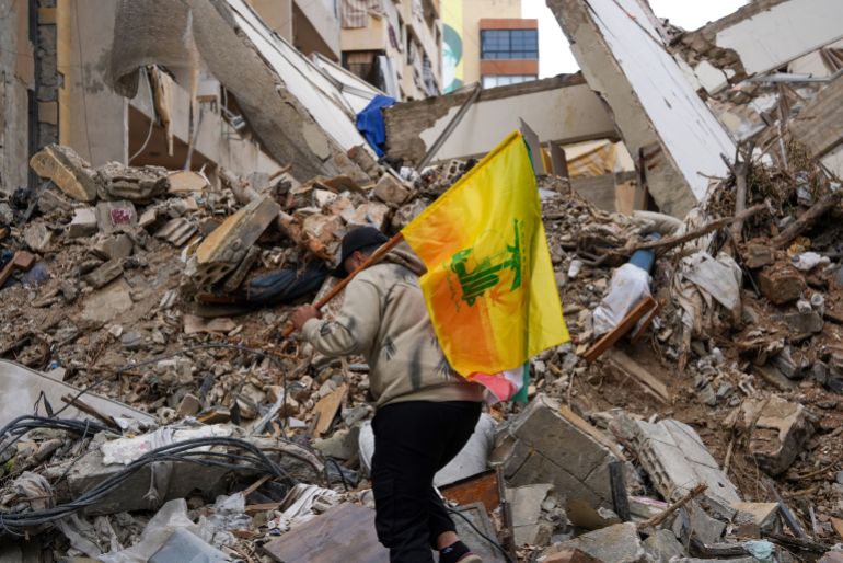 BEIRUT, LEBANON - APRIL 20: A man walks through the rubble of a building damaged by an Israeli air-strike while holding a Hezbollah flag in Beirut's southern suburb of Dahieh, on April 20, 2026 in Beirut, Lebanon. At 00:00 on April 17, a 10-day ceasefire took effect that is meant to pause fighting between Israeli forces and the Lebanese militant group Hezbollah. The agreement was announced the night before by U.S. President Donald Trump and described as a ceasefire between Israel and Lebanon; Hezbollah acknowledged the ceasefire but did not directly confirm it would abide by it. (Photo by Ryan Murphy/Getty Images)