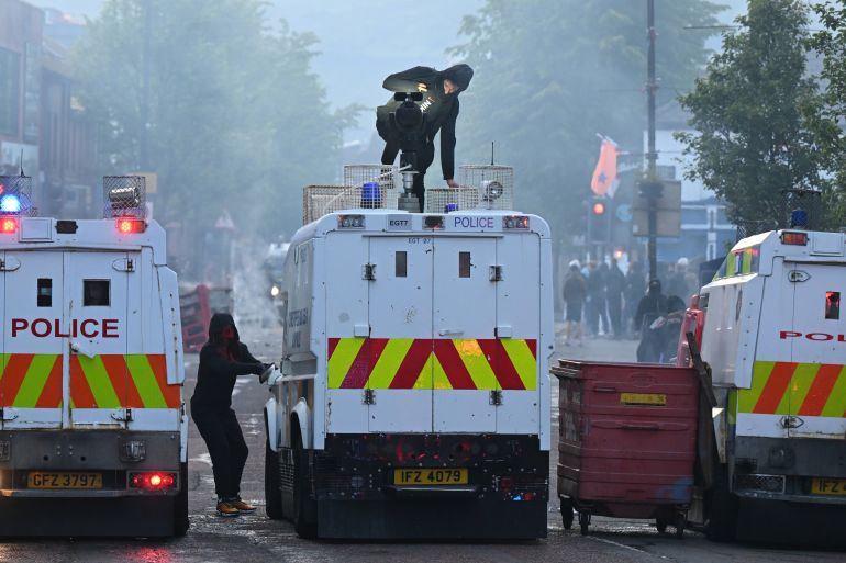 getty_6a290f35e3-1781075765 BELFAST, NORTHERN IRELAND - JUNE 9: Protestors attack a Police vehicle on Sandy Row on June 9, 2026 in Belfast, Northern Ireland. Demonstrations have been called in reaction to what police described as a "brutal" knife attack in north Belfast on Monday night, which has left a male victim in his 40's with serious injuries. The Home Office has confirmed the suspected knifeman is a Sudanese national who was in the UK on leave to remain, after being granted refugee status in 2023. Officials have called for calm as misinformation circulated online following the attack. (Photo by Charles McQuillan/Getty Images)