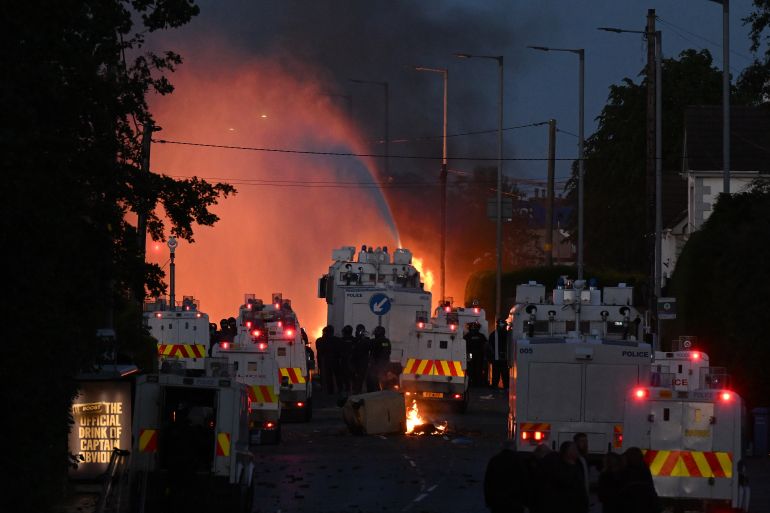 MALLUSK, NORTHERN IRELAND - JUNE 10: Police water canons spray water as fire burns during protests taking place near the Chimney Corner Hotel, which allegedly may be a hotel housing migrants, following a night of anti-immigrant riots on June 10, 2026 in Mallusk, Glengormley, Northern Ireland. Overnight protests in Belfast turned violent in reaction to a knife attack that took place on Monday night, which left a male victim in his 40's with serious injuries. Homes and vehicles were torched following the Home Office's confirmation that the suspected knifeman is a 30-year-old asylum seeker from Sudan, who was in the UK on leave to remain. Far-right influencers have been accused of stoking the violence by calling for anti-immigrant demonstrations after a graphic video of the stabbing attack went viral on social media. (Photo by Charles McQuillan/Getty Images)