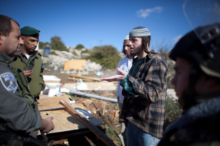 KIRYAT ARBA, WEST BANK - JANUARY 12: A Jewish settler talks to an Israeli border policeman after the Israeli army demolished their illegal West Bank outpost on January 12, 2012 in Mitzpe Avichai near Kiryat Arba in the West Bank.The unauthorised outpost has been flourishing in the past year, with ten wooden structures housing nine families in the southern West Bank. (Photo by Uriel Sinai/Getty Images)