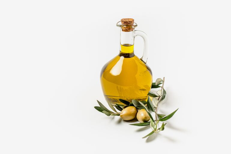 Olive oil in a bottle, green olives and olive tree branches isolated on white background - stock photo