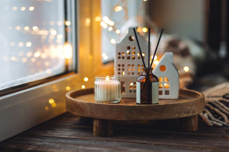 gettyimages-1877009102-1780327086 Natural Christmas essential oil, home aroma diffuser. Burning candles, branches of fir tree. Cinnamon, vanilla smell. Aromatherapy, cozy atmosphere, holiday festive mood. Close up macro, wooden table