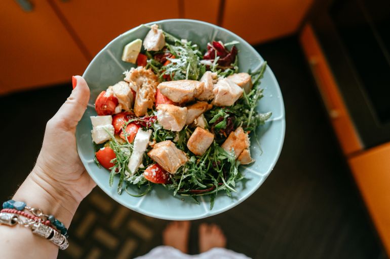 Women holding diet salad of tuna, green lettuce, arugula, seasoned with sesame seeds and mustard sauce. Healthy nutrition, protein low-calorie diet, gluten free