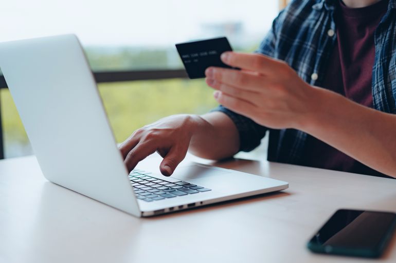 gettyimages-2161807222-1754768015 Young adult man entering credit card details to make online payment. Online shopping concept. Travel planning. Booking a holiday online.