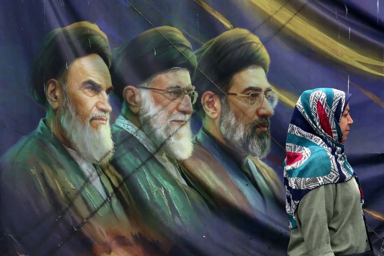 iran119-1780844799-1 An Iranian woman walks past a banner bearing portraits of the late founder of the Islamic Republic, Ayatollah Ruhollah Khomeini (L), former supreme leader Ayatollah Ali Khamenei (C), who was assassinated in February 2026, and current supreme leader Mojtaba Khamenei (R), in Tehran on May 28, 2026. Iran's foreign ministry condemned on May 28, what it called violations by the United States after its strikes on the southern port city of Bandar Abbas and expressed solidarity with Oman after the US president threatened to "blow them up". (Photo by AFP) /
