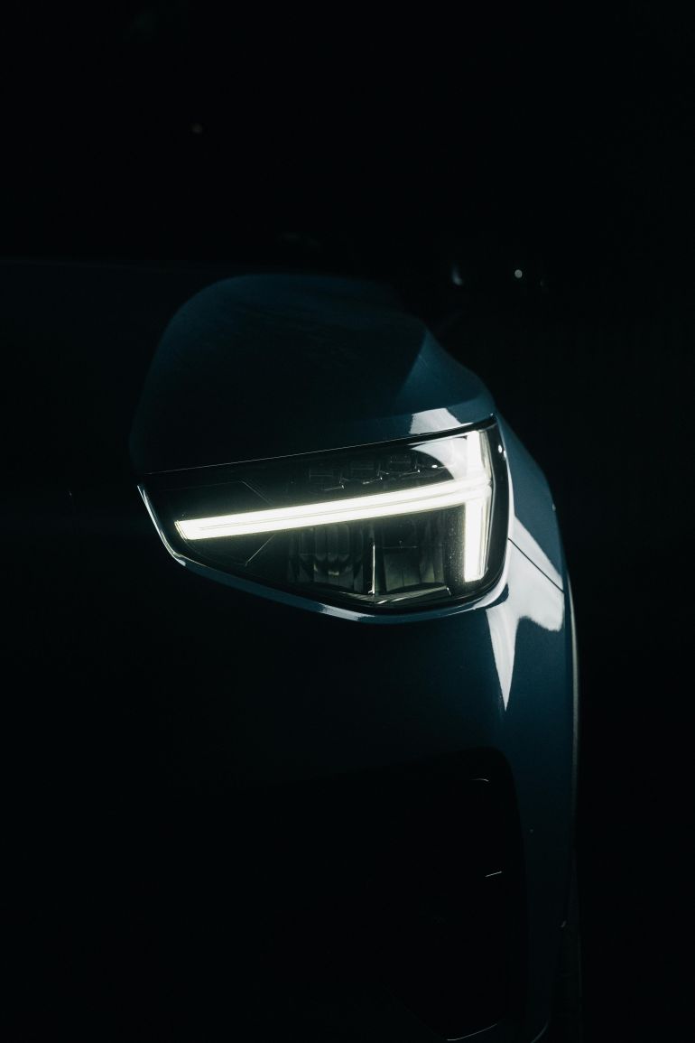 Close-up of a modern car headlight illuminated against a dark background.