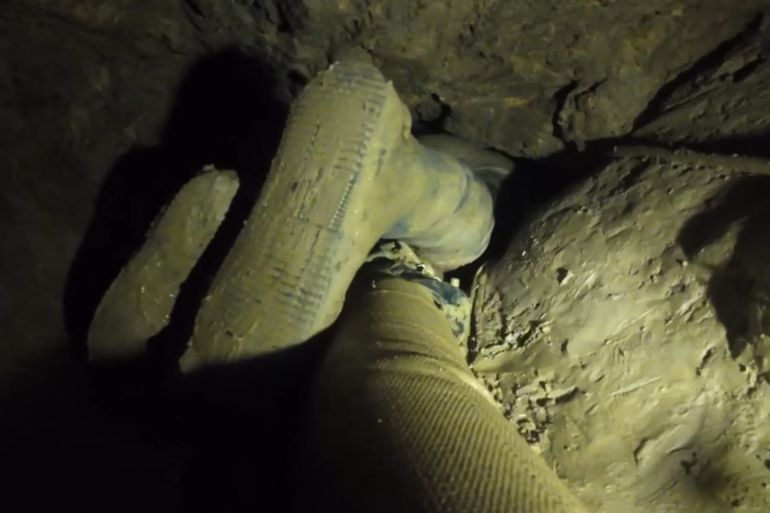 This screengrab made from handout video footage taken on May 27, 2026, and provided by Benz Norrased Palasing of Seascout Diving, shows the shoes of a rescue worker as he pulls himself through a narrow section of a flooded cave in Laos' central Xaysomboun province, northeast of the capital Vientiane. Rescuers rushed on May 28 to pump water from a flooded cave in Laos, where seven Laotians have been trapped for more than a week, with the fate of two of them unknown. (Photo by Handout / Benz Norrased Palasing / Seascout Diving / AFP) / -----EDITORS NOTE --- RESTRICTED TO EDITORIAL USE - MANDATORY CREDIT "AFP PHOTO / Benz Norrased Palasing / Seascout Diving " - NO MARKETING - NO ADVERTISING CAMPAIGNS - DISTRIBUTED AS A SERVICE TO CLIENTS - NO ARCHIVE