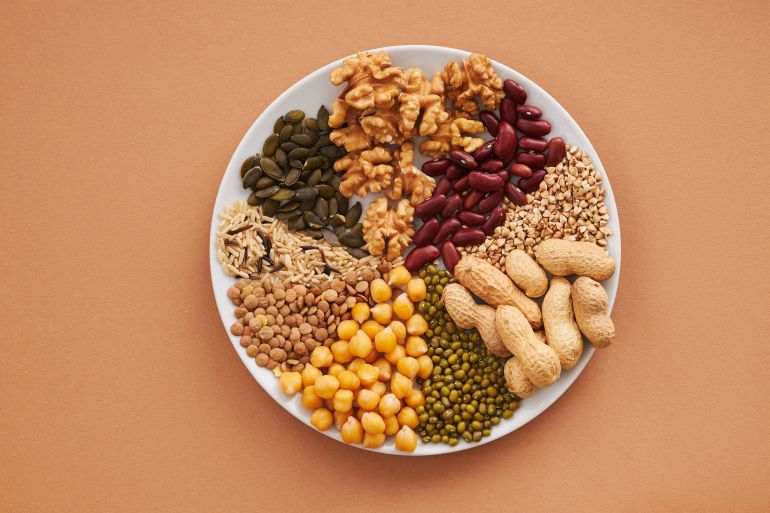 mksrat-bdhwr-1781123090 Top view of nuts, beans, and seeds on a plate, ideal for healthy dining themes.