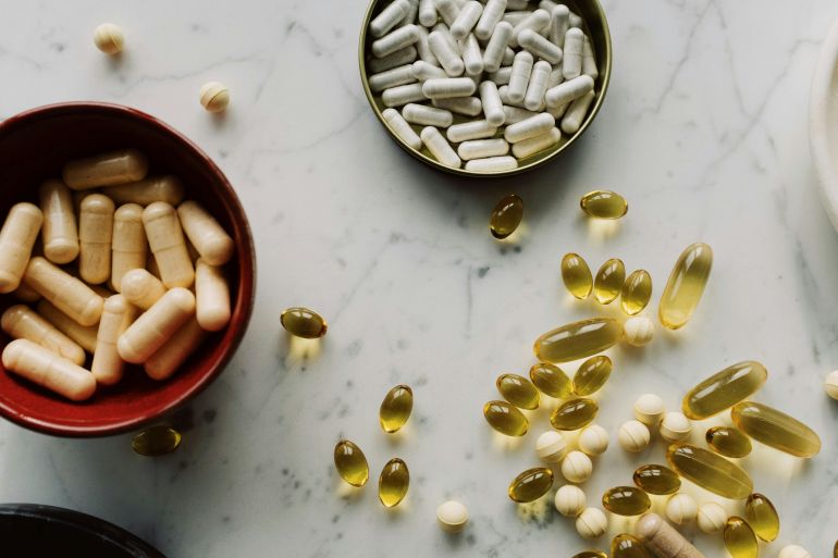 mmlat-1779696156 Top view of various supplements and capsules arranged on a marble surface with ample copy space.