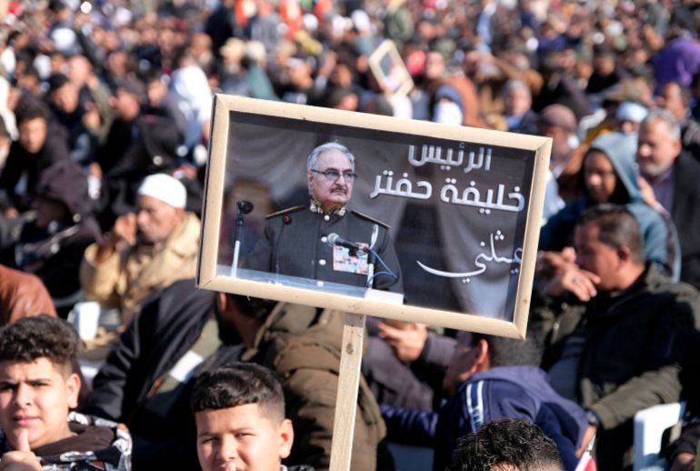 rc2ccy9qjm0f-1781722050 A man holds a picture of commander Khalifa Haftar during Independence Day celebrations in Benghazi, Libya December 24, 2022. REUTERS/Stringer REFILE - UPDATING BYLINE (رويترز)
