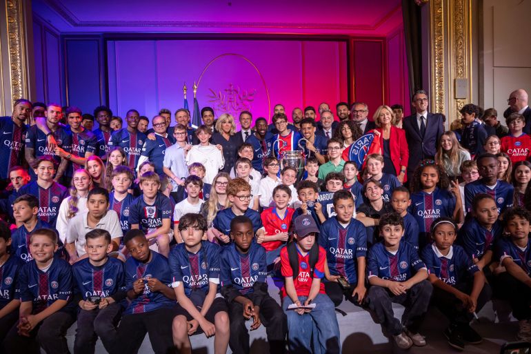 French President Emmanuel Macron poses with children and Paris Saint-Germain team players with the trophy during a reception at the Elysee Palace in Paris, France, May 31, 2026. Paris Saint-Germain won the UEFA Champions League for the second time after beating Arsenal FC in the final in Budapest. Christophe Petit Tesson/Pool via REUTERS