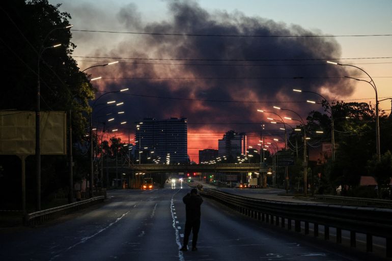 A man takes a picture of a street as smoke rises in the background after an overnight Russian missile and drone strike, amid Russia's attack on Ukraine, in Kyiv, Ukraine June 2, 2026. REUTERS/Alina Smutko TPX IMAGES OF THE DAY