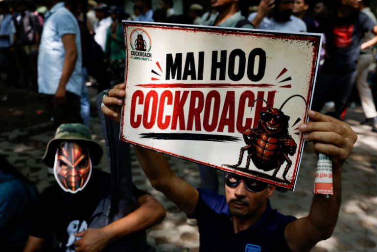 A person wearing a mask holds a poster which reads "I am a Cockroach", as supporters of the Cockroach Janta Party (CJP) await the arrival of Abhijeet Dipke, head of the CJP, on the day of a sit-in protest demanding the resignation of Indian Education Minister Dharmendra Pradhan, in New Delhi, India, June 6, 2026. REUTERS/Adnan Abidi TPX IMAGES OF THE DAY