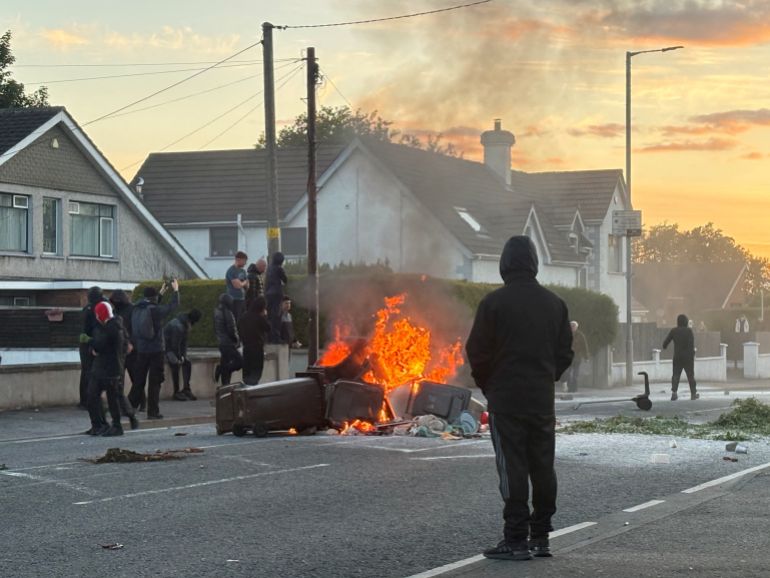 reuters_6a2a398c-1781152140 A fire burns in bins as anti-immigrant protesters clash with police at Antrim road, following a knife attack on June 8, which left a man seriously injured and prompted police to declare a critical incident, in Belfast, Northern Ireland, June 10, 2026. Picture taken with a phone. REUTERS/Isabel Infantes TPX IMAGES OF THE DAY
