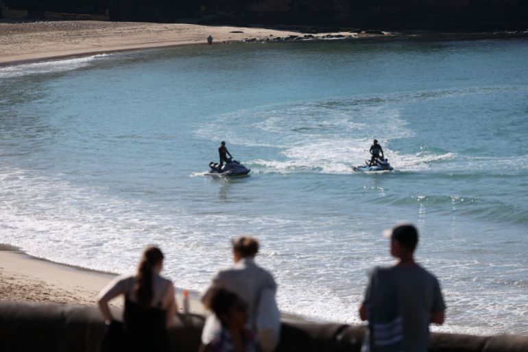 reuters_6a2cf152-1781330258 Lifeguards patrol Coogee Beach on jet skis after reports of a shark attack in Sydney, Australia, June 13, 2026. REUTERS/Hollie Adams
