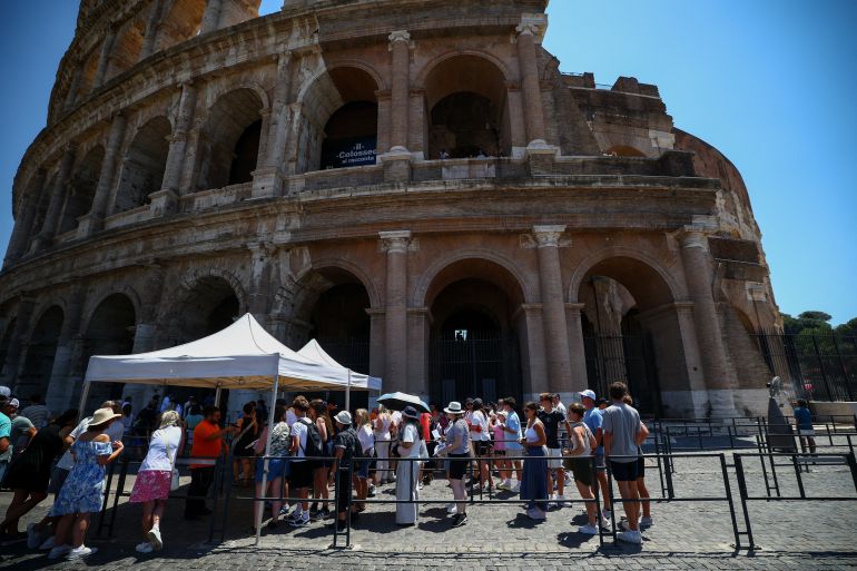 reuters_6a36bcc4-1781972164 Visitors use umbrella for shade as they queue at the entrance to the Colosseum during a heatwave in Rome, Italy, June 20, 2026. REUTERS/Guglielmo Mangiapane