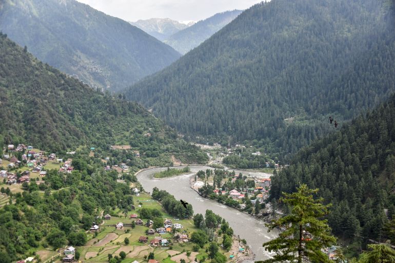 This photograph taken on May 29, 2026 shows an aerial view of the Keran sector along the Neelum River with villages on both sides of the Line of Control, with Pakistan-administered Kashmir on one bank and Indian-administered Kashmir on the other, separated by the narrow mountain river that divides the valley, as seen from Keran village in Pakistan-administered Kashmir. Kashmir resident Raja Basharat can see his brother's grave on the opposite bank of a river that divides the disputed region, but visiting it -- a holiday tradition for Muslims on Eid al-Adha -- is impossible. (Photo by Sajjad QAYYUM / AFP) / To go with "Pakistan-India-Kashmir-Conflict-Religion" Reportage by Sajjad Qayyum (الفرنسية)