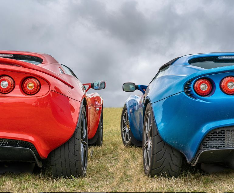 sbwr-1780323812 Two vibrant sports cars in a grassy landscape, showcasing modern design and bright colors.
