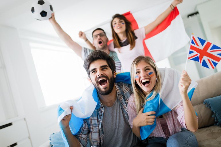 Soccer fans emotionally watching game in the living room.