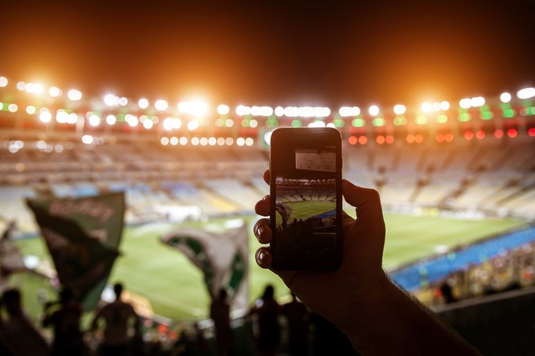 shutterstock_1648635313-1780913909 Smartphone photographing football game on the stadium.