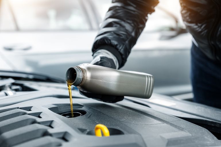 Close-up driver hand holding small bottle can pouring synthetic motor oil in diesel or petrol turbocharged vehicle engine due oil consumption. New lubricant diy change. Car service maintenance work; Shutterstock ID 2284208965; purchase_order: aj; job: ; client: ; other: