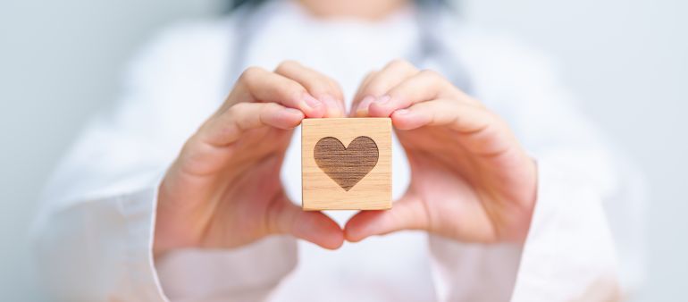 shutterstock_2416367329-1778238730 Doctor hand holding heart shape block in hospital. love, donor, world heart day, world health day, CSR donation and Insurance concepts